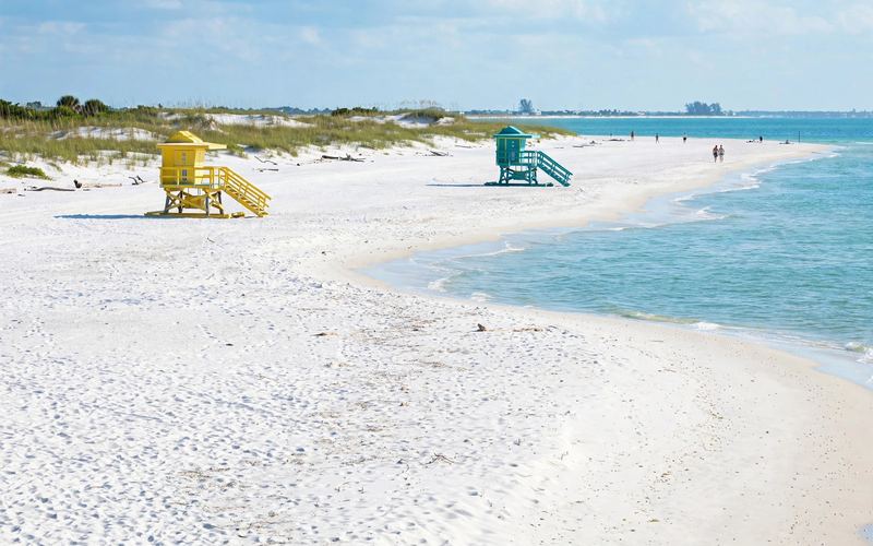White sand and turquoise water at a Sarasota beach with colorful lifeguard stands